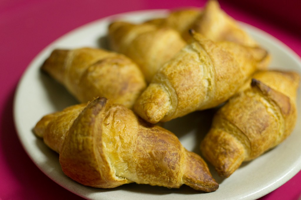 Five croissants piled on a pale plate