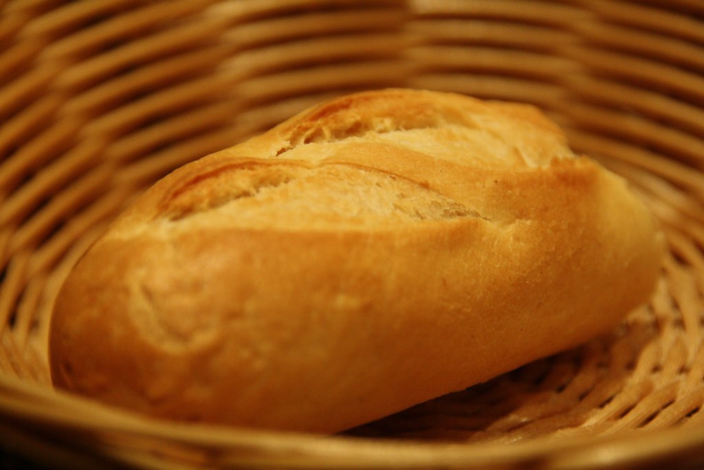 A small pale loaf lying in a round wicker basket