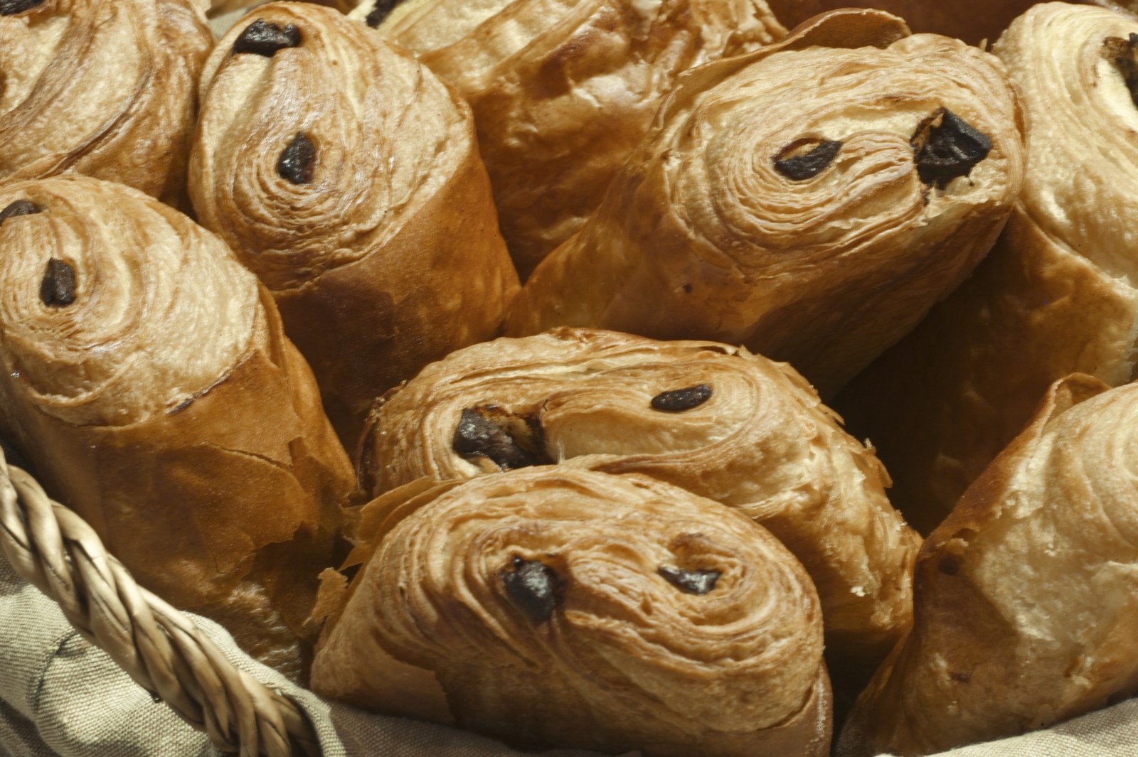 Pains au chocolat packed close together in a cloth-lined basket